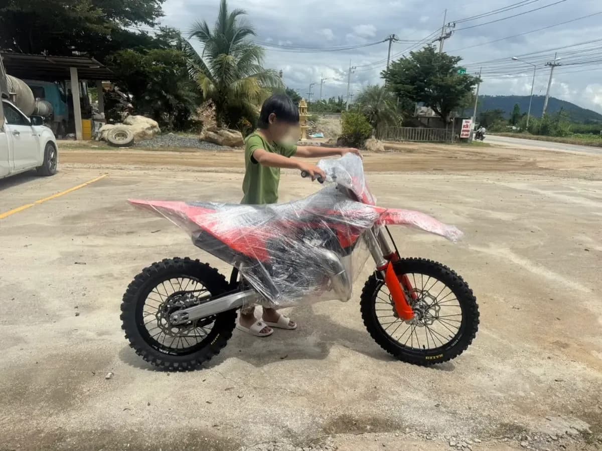 รถวิบากสีแดงขาวห่อฟิล์มหลังขนลงจากรถ