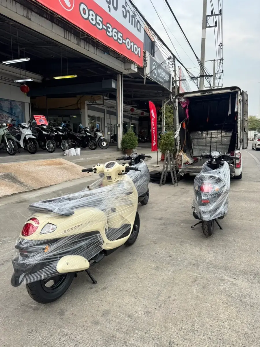 Film-wrapped cream scooter outside the dealer, ready to load