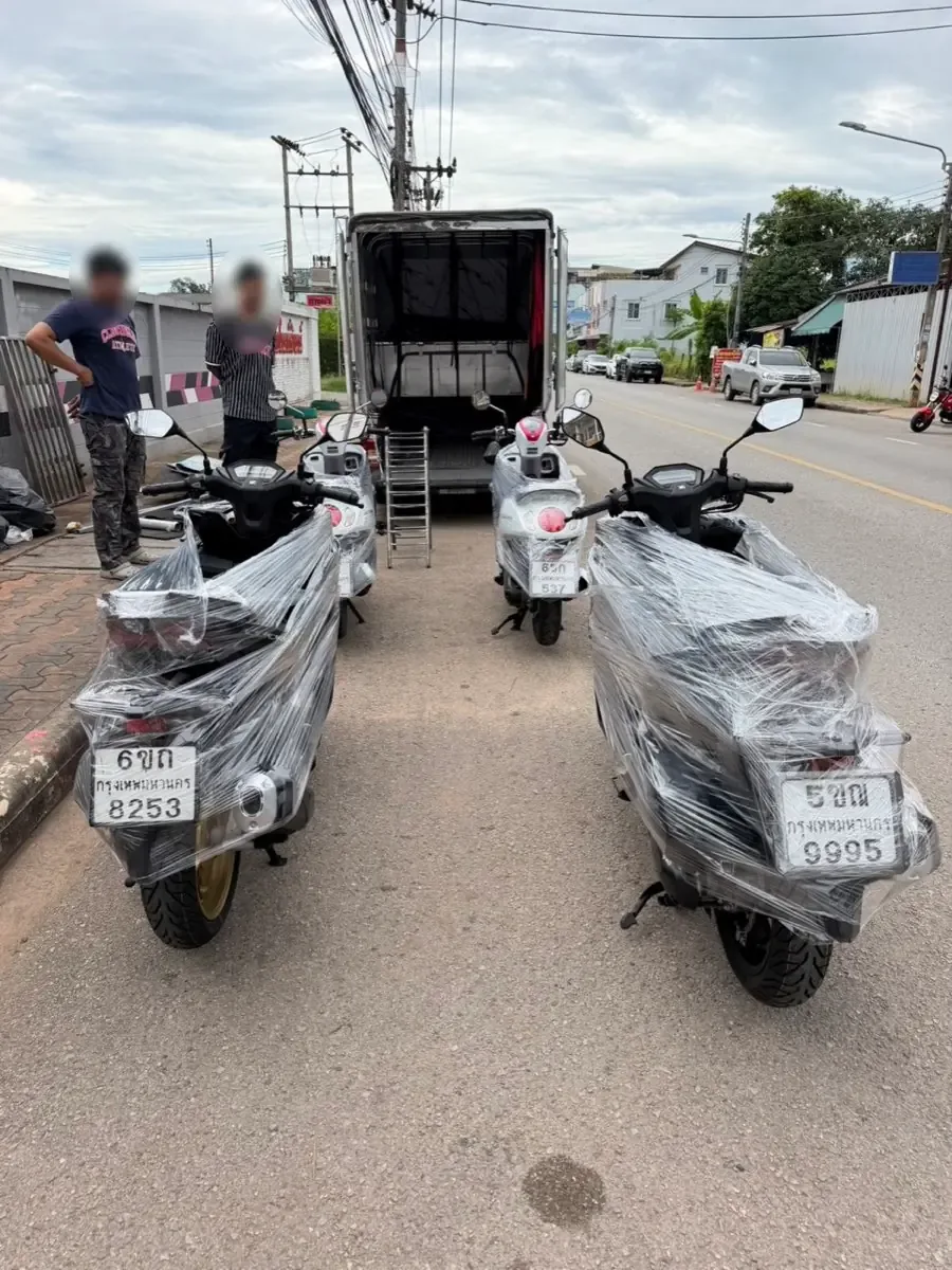 Two film-wrapped scooters beside the box truck