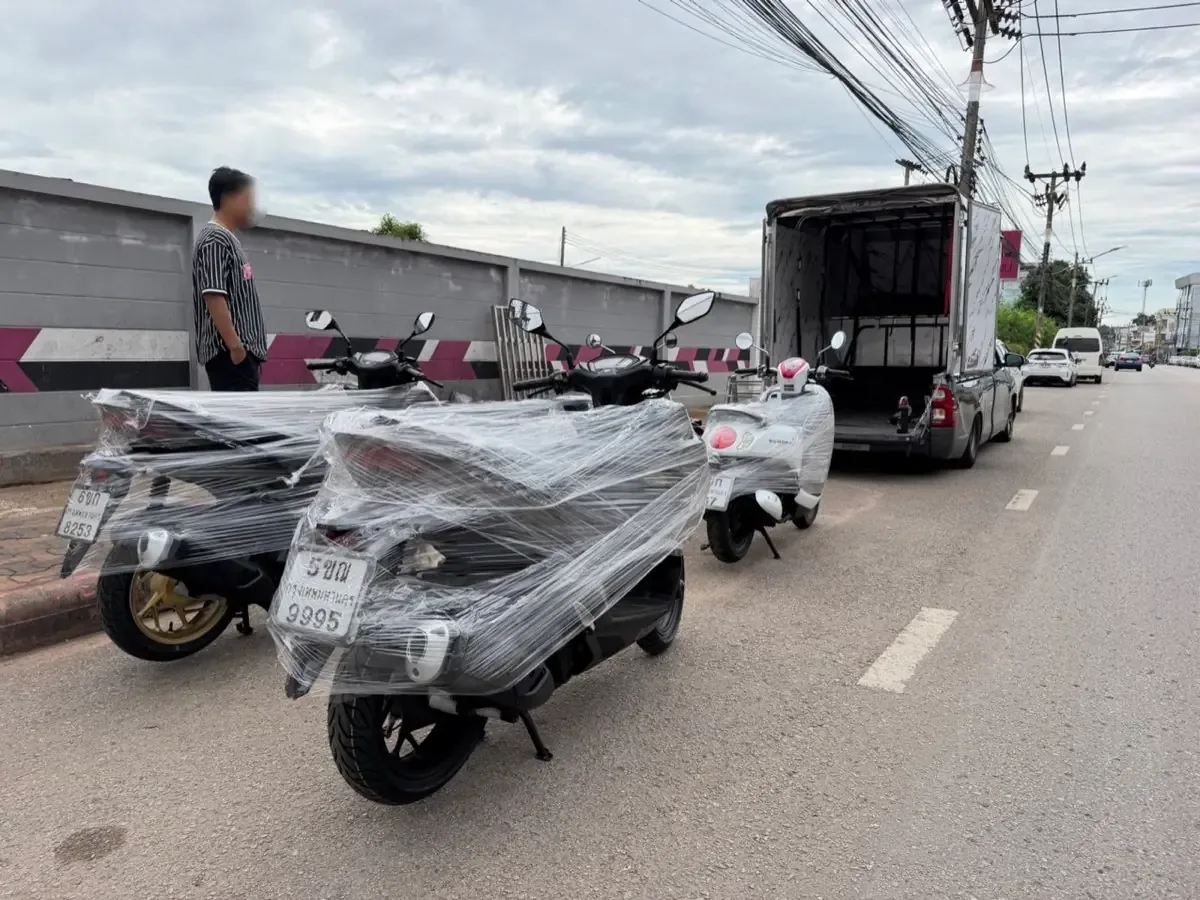 Film-wrapped scooters lined up at the roadside before loading